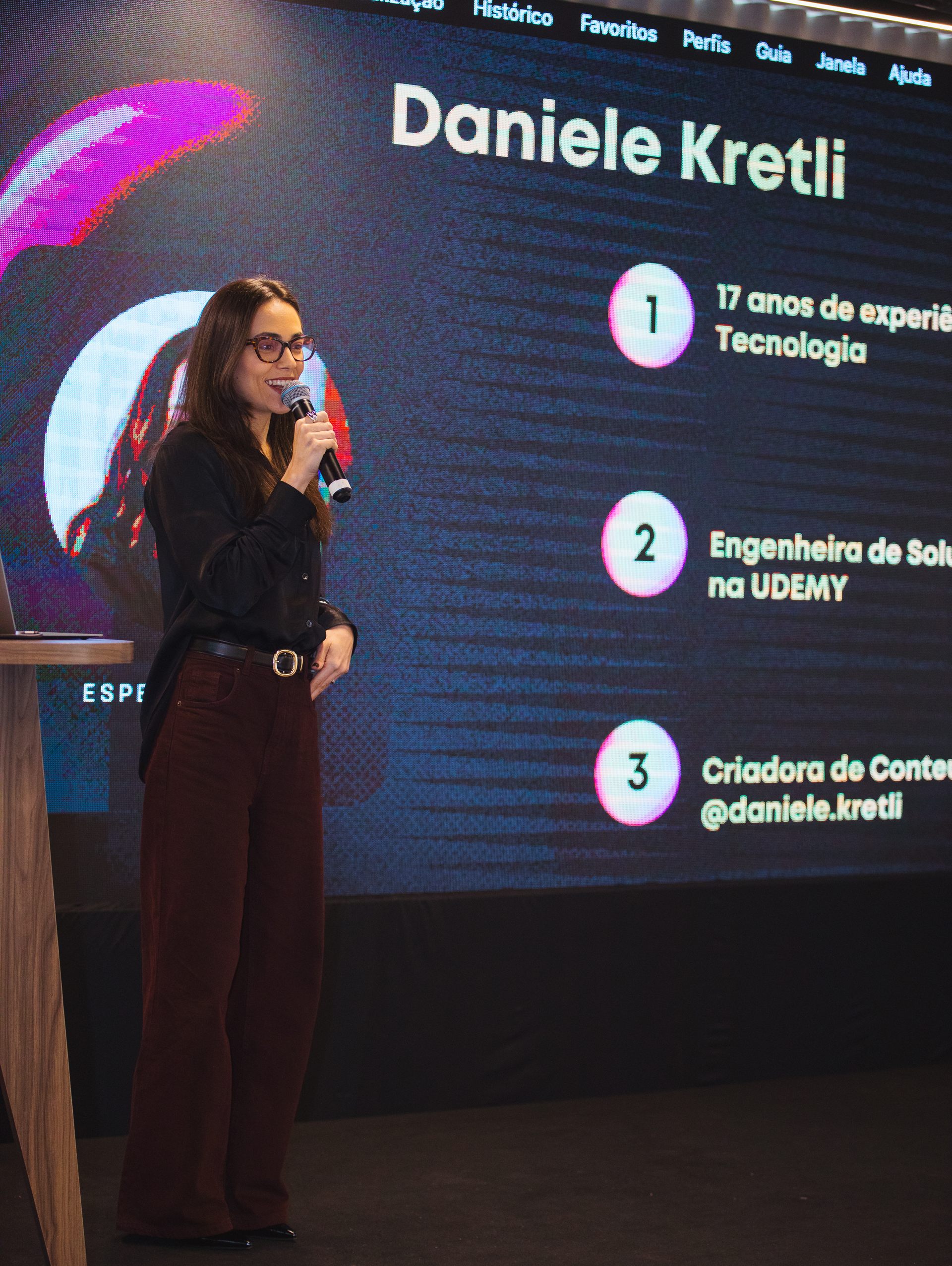 Daniele Kretli em palestra apresentando o slide com sua trajetória